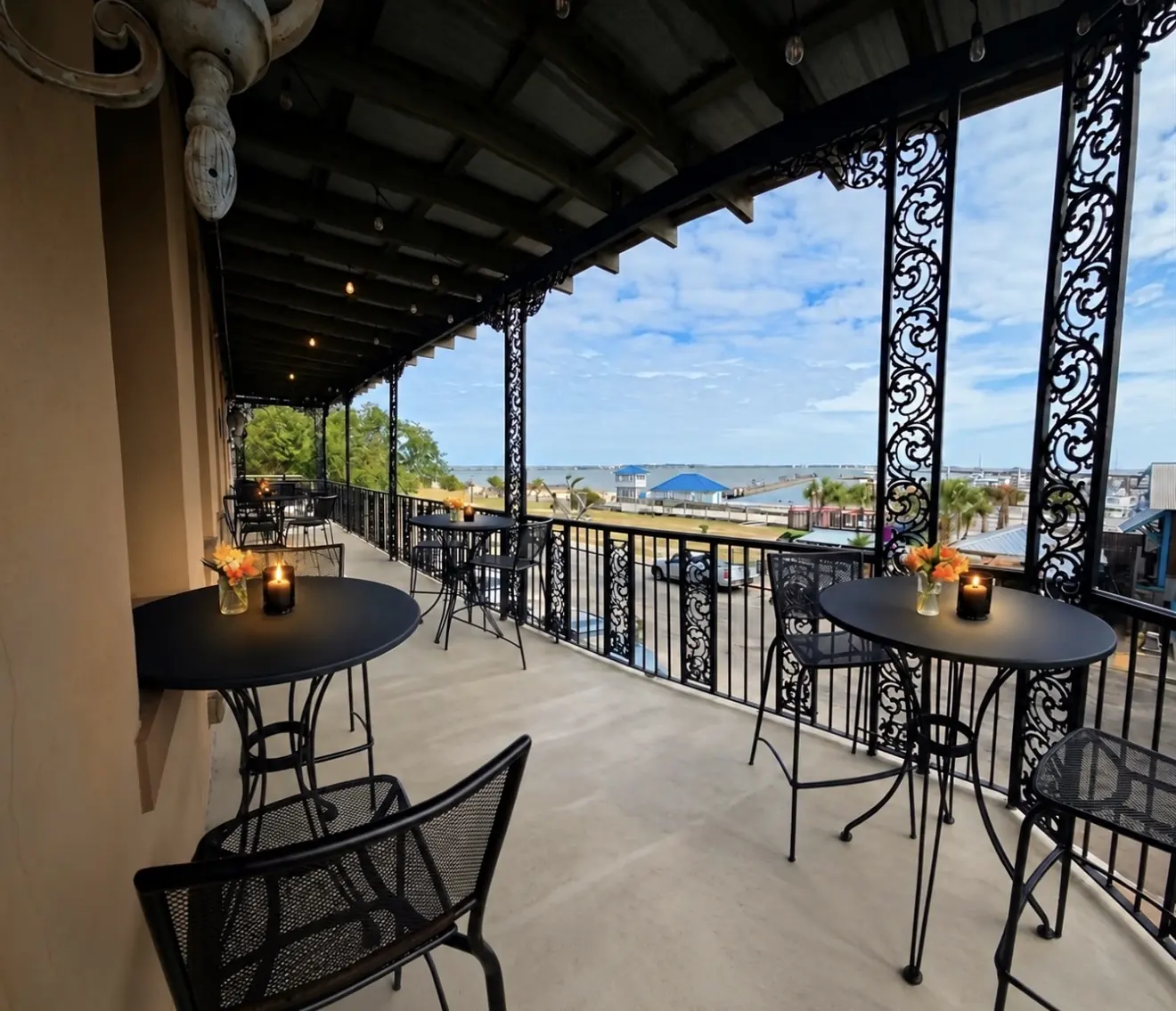 The upstairs balcony at 200 North Beach, with iron railings framing the Bay of St. Louis