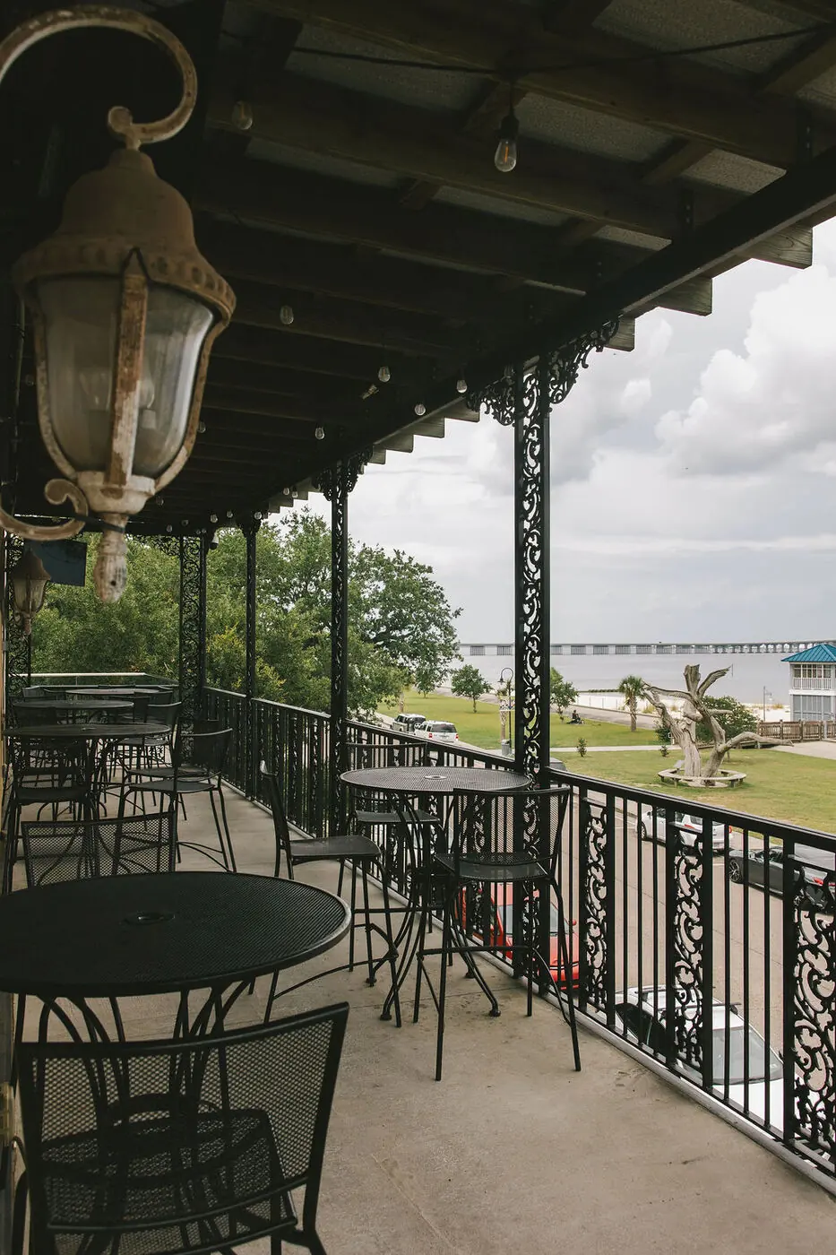 The upstairs balcony at 200 North Beach, with iron railings framing the Bay of St. Louis