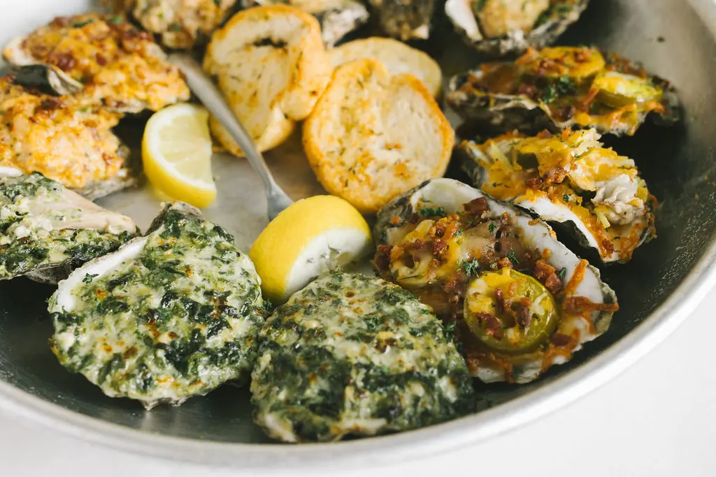 A tray of chargrilled oysters with lemon and toasted bread