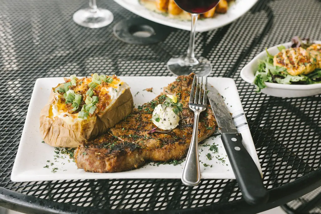 A ribeye dinner with red and white wine on the balcony
